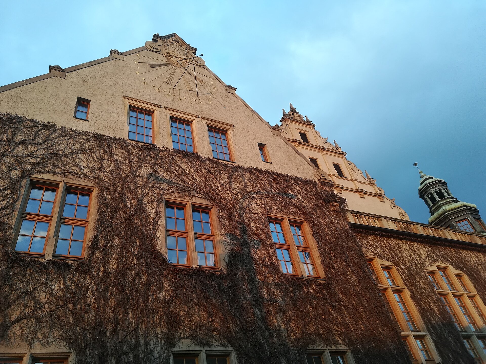 Collegium Minus UAM — fasada z zegarem słonecznym i bluszczem